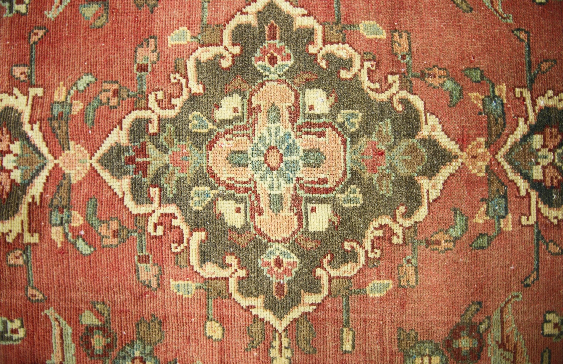 A vintage Persian runner featuring a central floral medallion in olive green on a terracotta field.