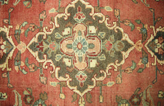 A vintage Persian runner featuring a central floral medallion in olive green on a terracotta field.