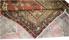 A vintage Persian runner with a folded corner showing its intricate floral pattern and wool weave.