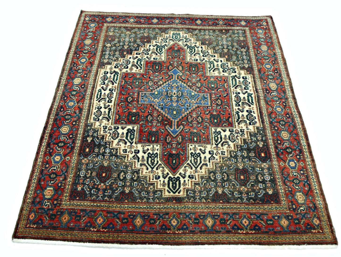 A vintage Persian Senneh rug featuring a central blue diamond medallion on a red and dark field.