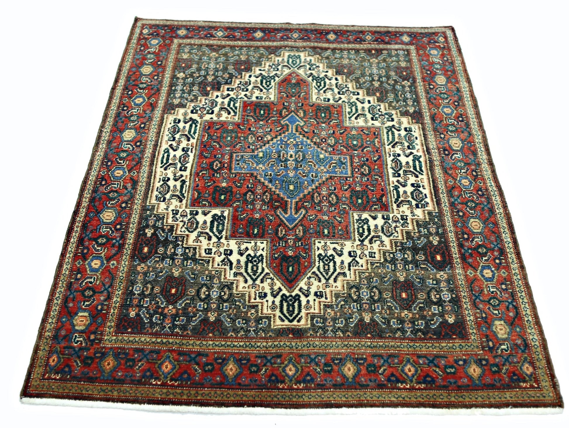A vintage Persian Senneh rug featuring a central blue diamond medallion on a red and dark field.