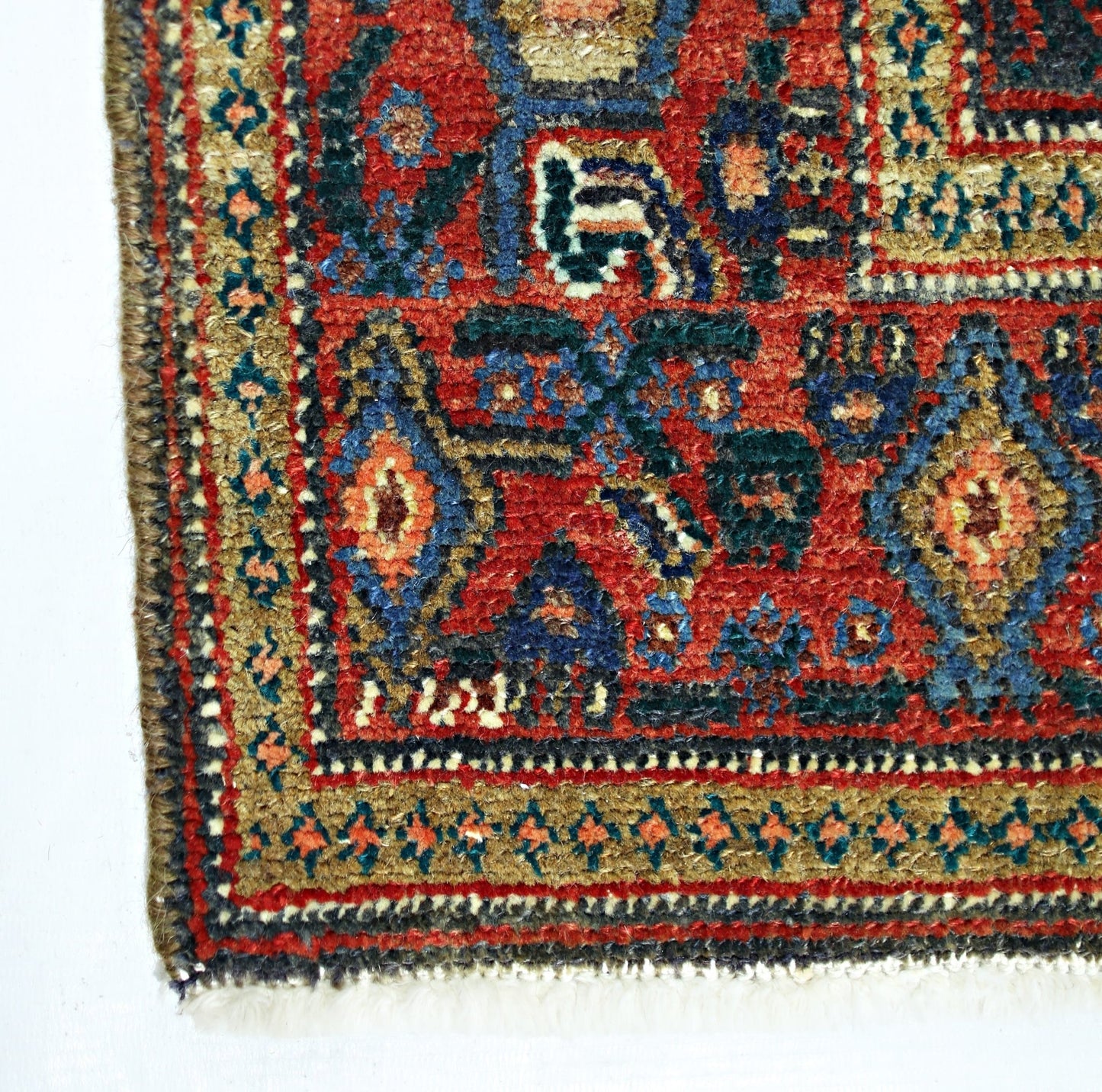 A vintage Persian Senneh rug featuring intricate geometric patterns in red, blue, and gold tones.