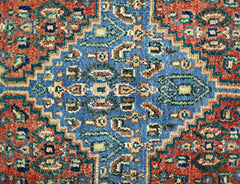A vintage Persian Senneh rug featuring a central blue medallion with intricate geometric patterns.