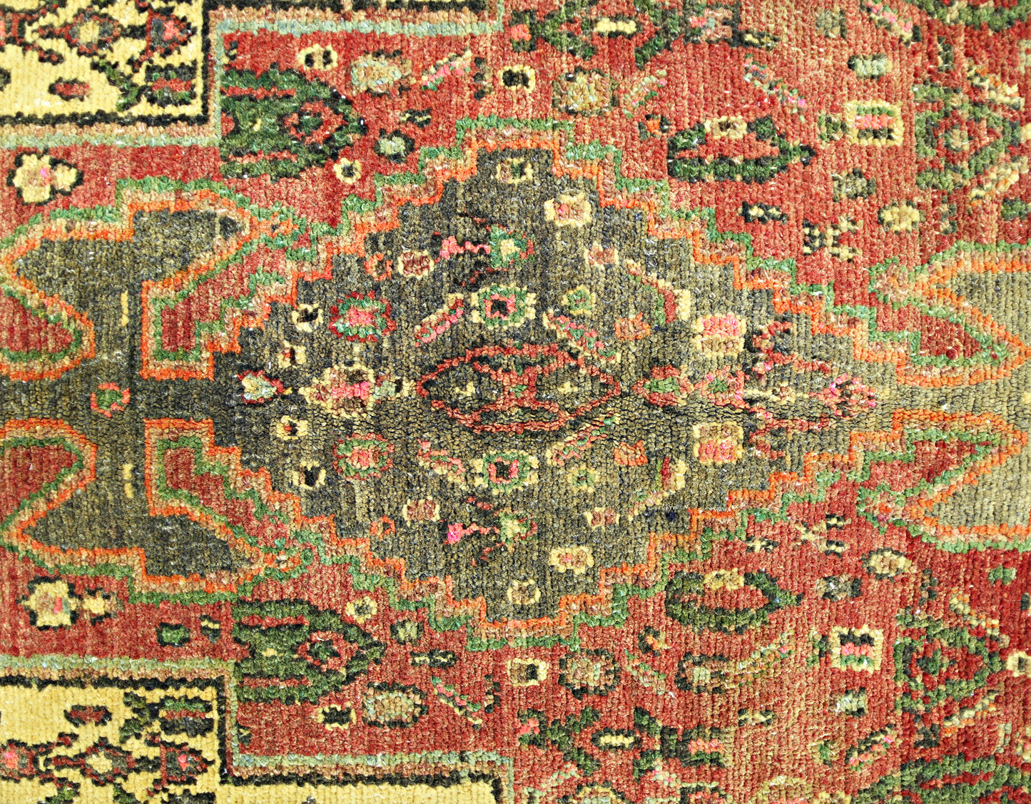 A vintage Persian Sanandaj rug featuring a detailed geometric medallion in red, green, and gold.
