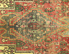 A vintage Persian Sanandaj rug featuring a detailed geometric medallion in red, green, and gold.