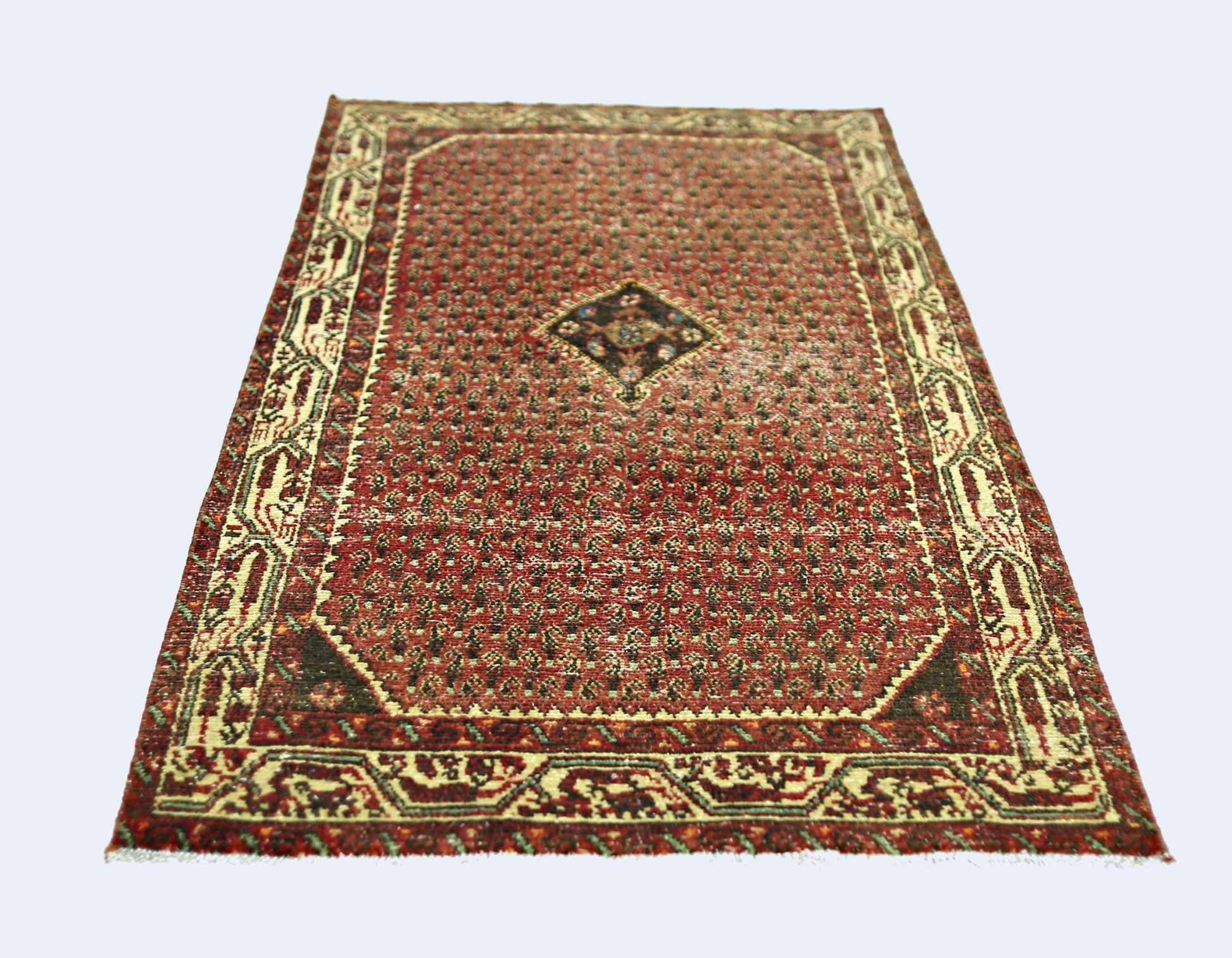A vintage Persian Saraband rug featuring a red field with a repeating pattern and a central diamond.