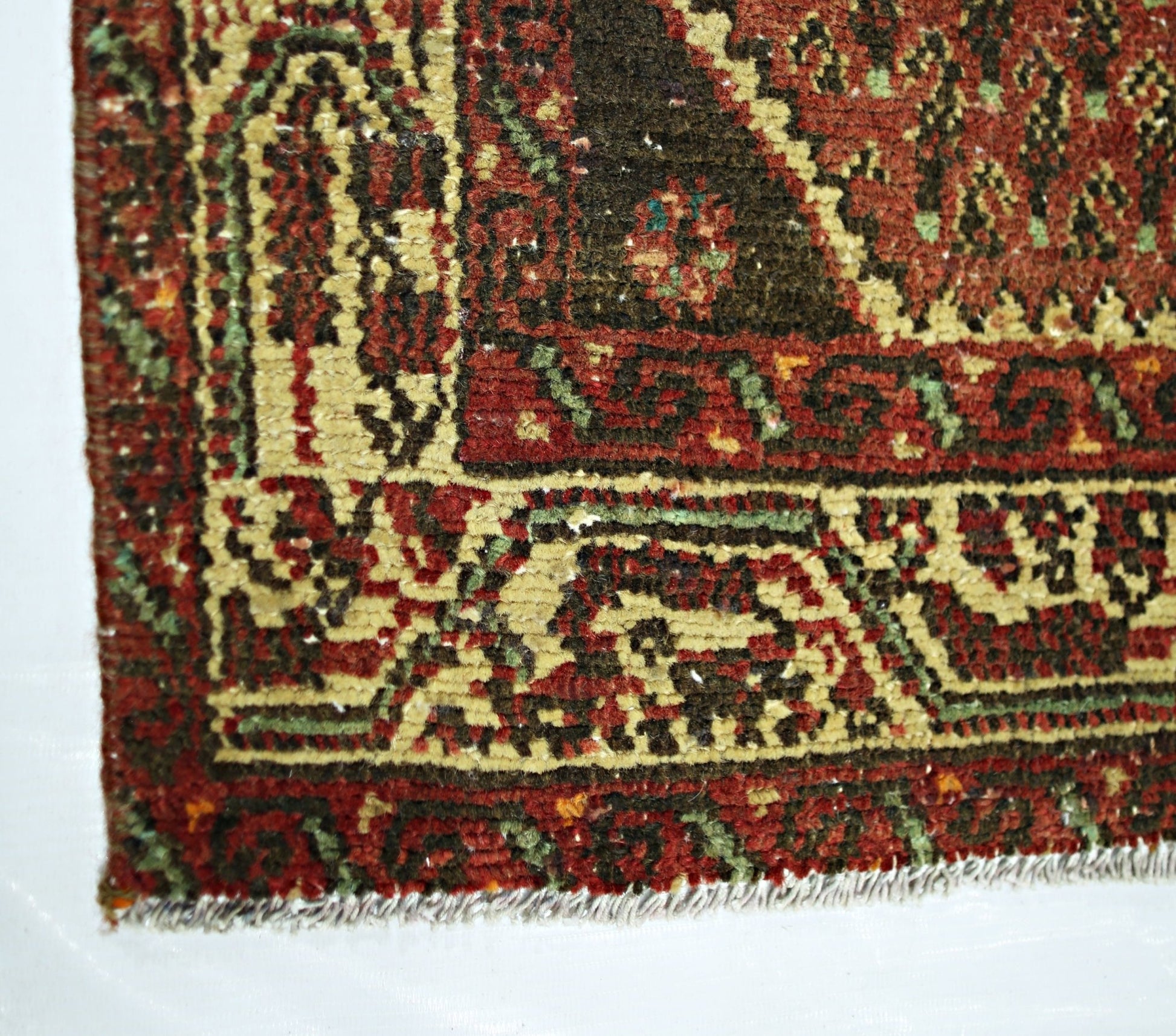 A corner view of a vintage Persian Saraband rug featuring a traditional red and dark brown pattern.