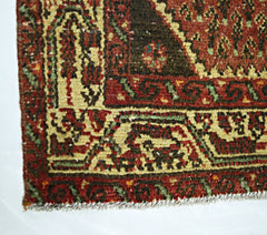 A corner view of a vintage Persian Saraband rug featuring a traditional red and dark brown pattern.