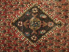 A vintage Persian Saraband rug featuring a central diamond medallion on a red patterned field.