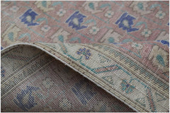 A handwoven vintage Persian rug featuring a faded floral pattern in blue, green, and pink tones.