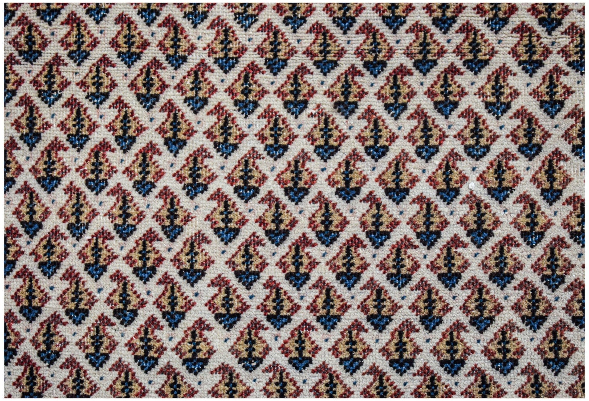 A vintage Persian Saraband rug featuring a repeating blue and red paisley pattern on a cream base.