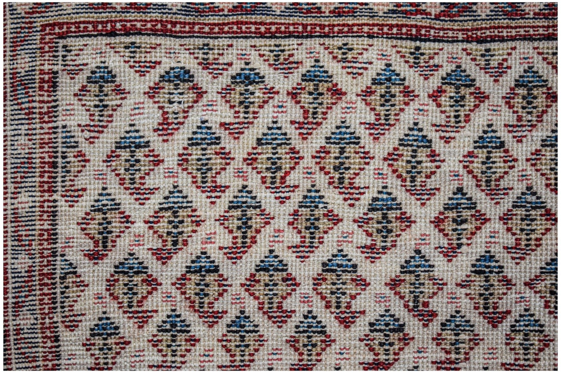 A vintage Persian Saraband rug featuring a repeating blue and tan boteh pattern on a cream field.