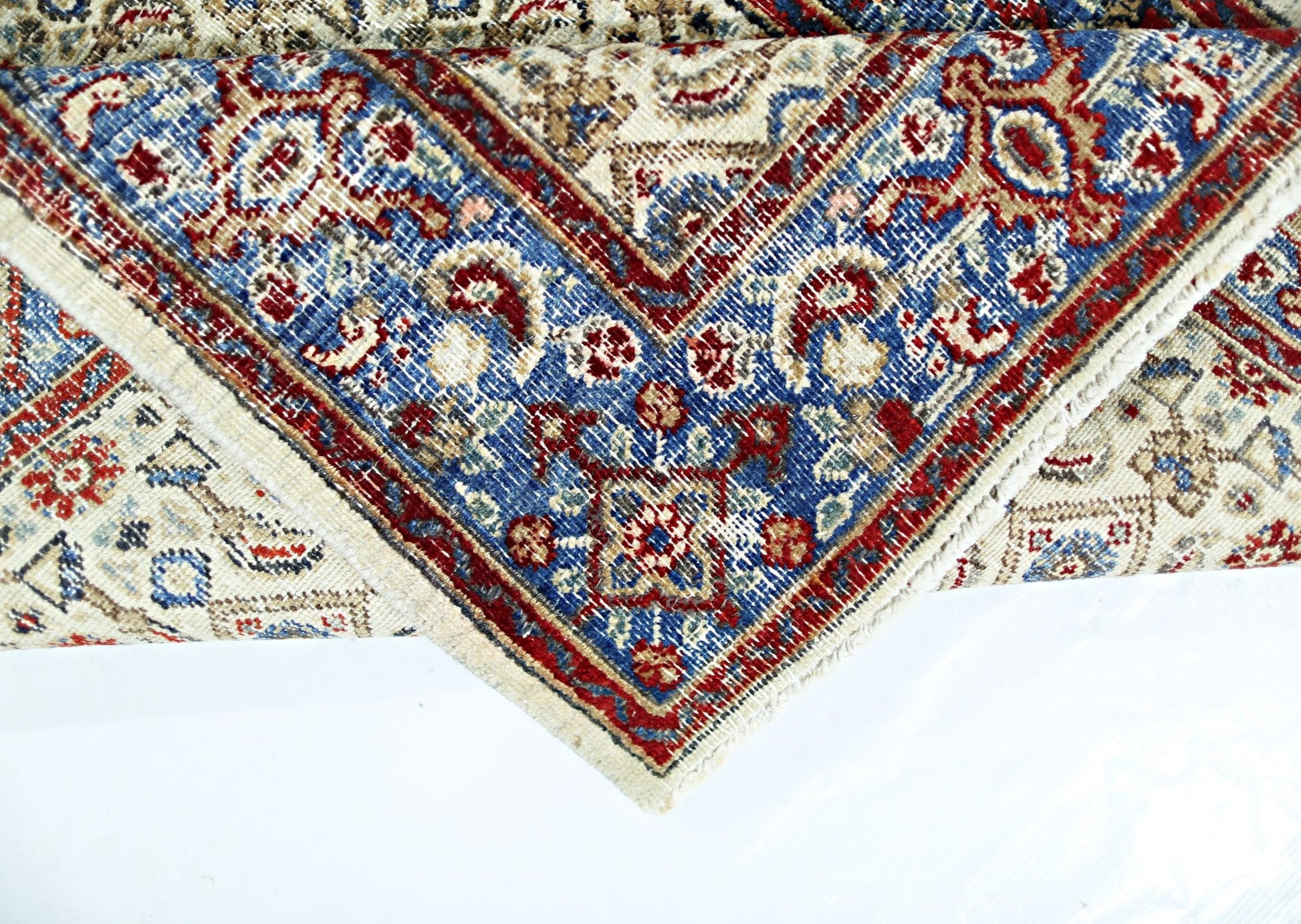 A vintage Persian Saraband rug featuring a blue border with intricate red and cream floral patterns.