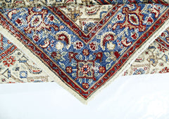 A vintage Persian Saraband rug featuring a blue border with intricate red and cream floral patterns.