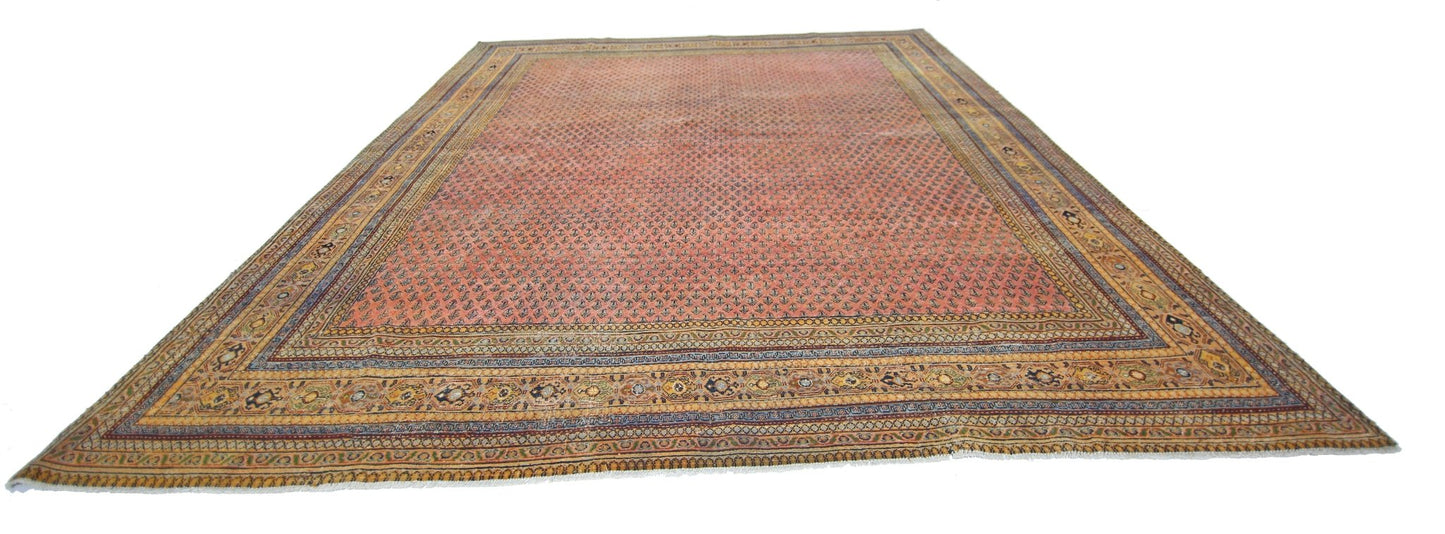A vintage Persian Saraband rug featuring a repeating floral pattern on a salmon-pink field.