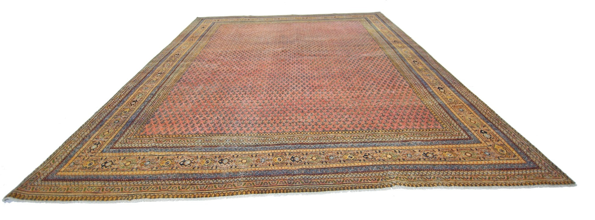 A vintage Persian Saraband rug featuring a repeating floral pattern on a salmon-pink field.
