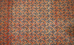 A vintage Persian Saraband rug featuring a dense, repeating geometric pattern in orange and blue.