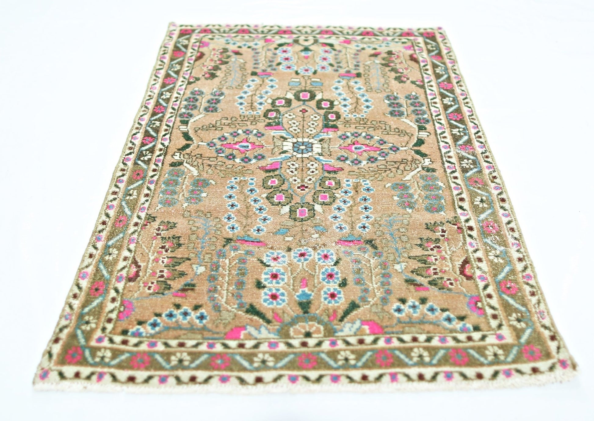A vintage Persian Sarouk rug featuring a floral pattern in pink, blue, and green on a tan field.