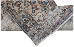A handwoven vintage Persian rug with a faded floral pattern in blue, brown, and cream tones.