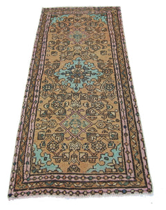 A vintage Persian runner rug featuring a geometric floral pattern in shades of tan, blue, and pink.