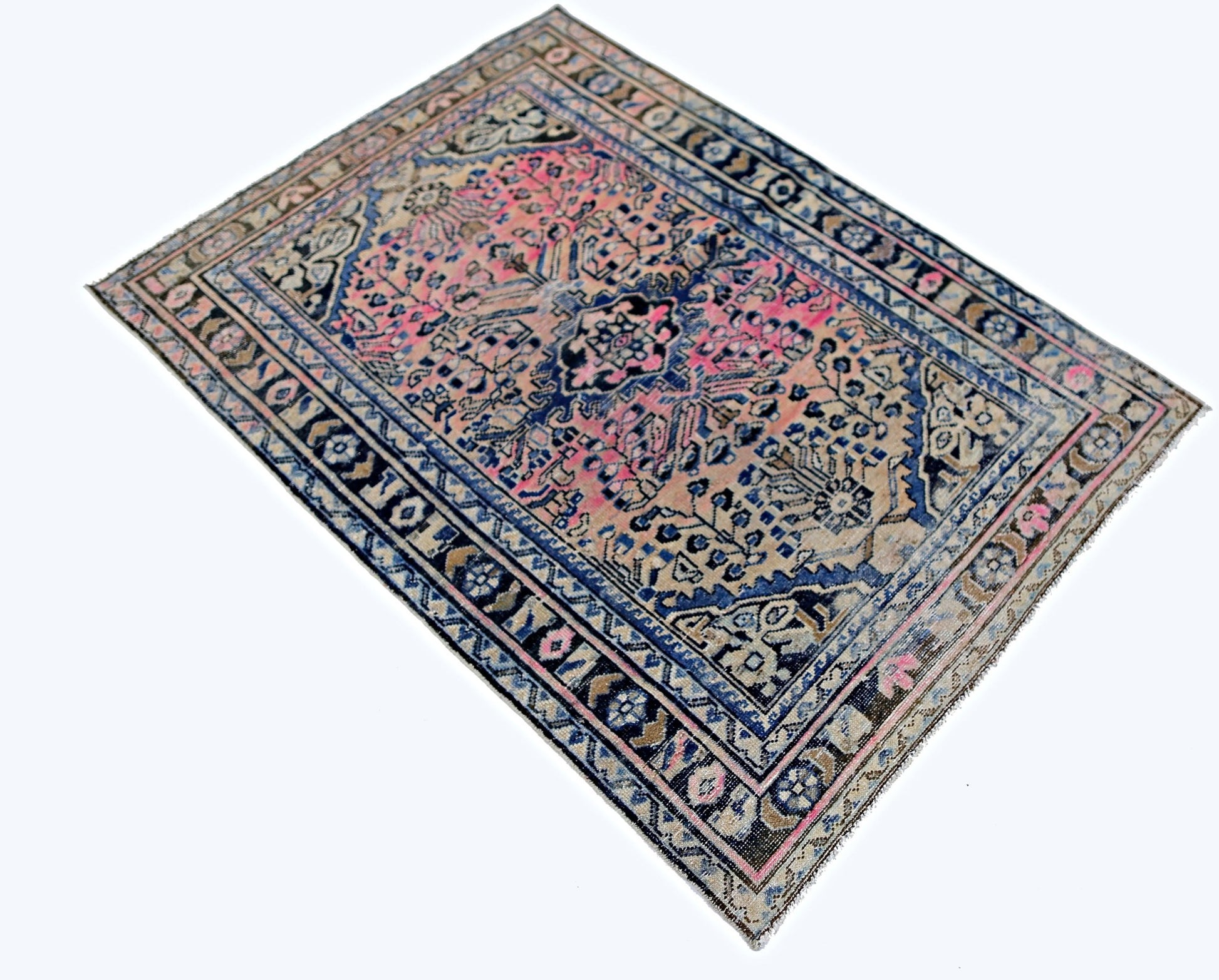 A vintage handmade Persian rug featuring a central floral medallion in pink and blue tones.