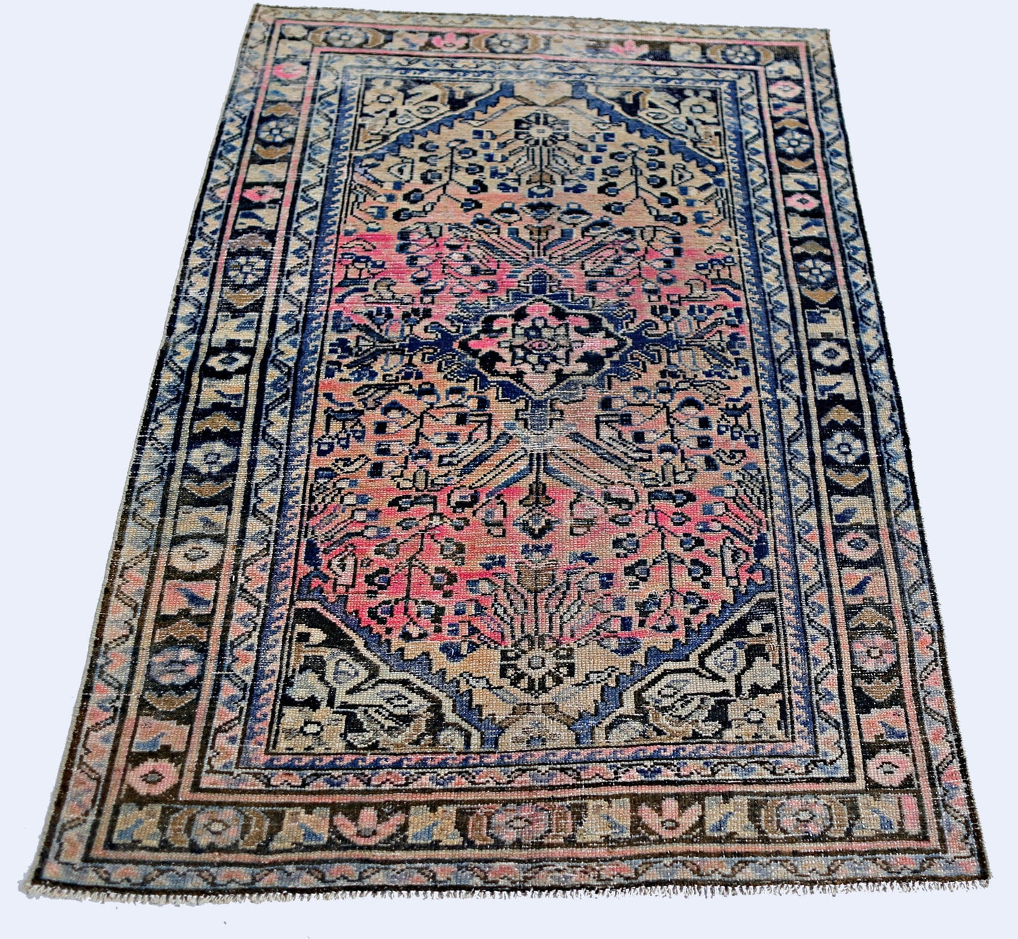 A vintage Persian rug featuring a central medallion with pink and blue floral patterns.