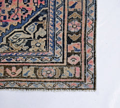 A vintage Persian rug featuring a detailed floral pattern in shades of blue, pink, and beige.