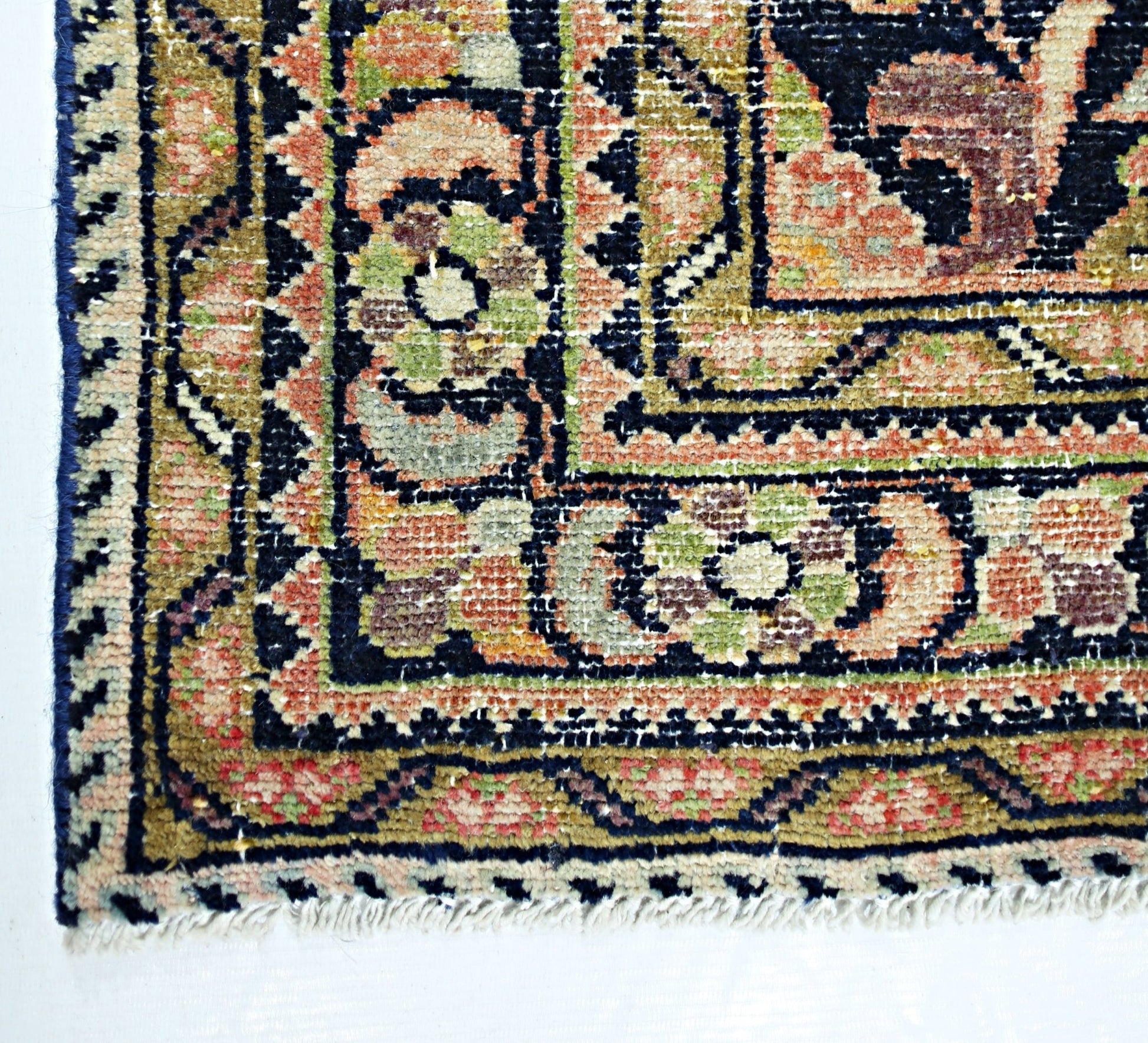 A corner view of a handmade vintage Persian rug featuring intricate floral patterns in wool.