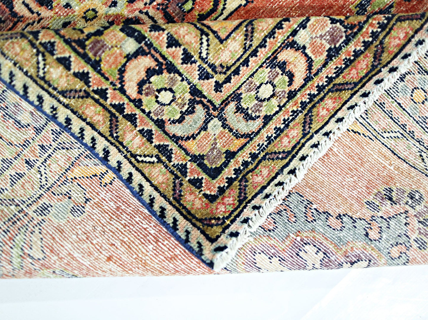 A folded vintage Persian rug featuring intricate geometric patterns in warm, earthy tones.