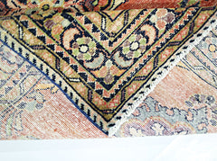 A folded vintage Persian rug featuring intricate geometric patterns in warm, earthy tones.