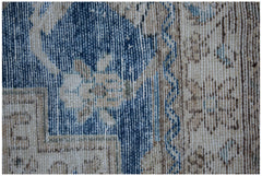 A close-up of a vintage Persian Sarouk rug featuring intricate floral patterns in blue and beige.