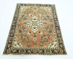 A vintage Persian Sarouk rug featuring a floral medallion on a salmon field with a dark border.