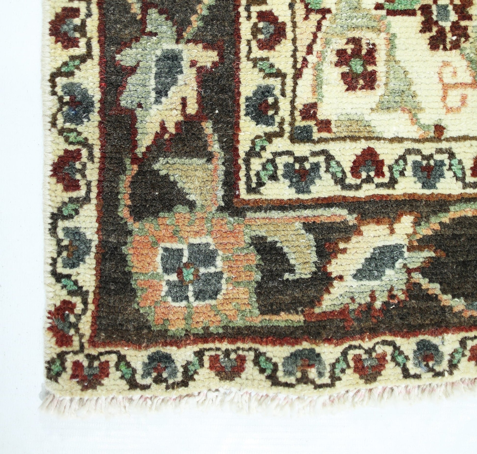 A corner view of a vintage Persian Sarouk rug featuring intricate floral patterns in wool.