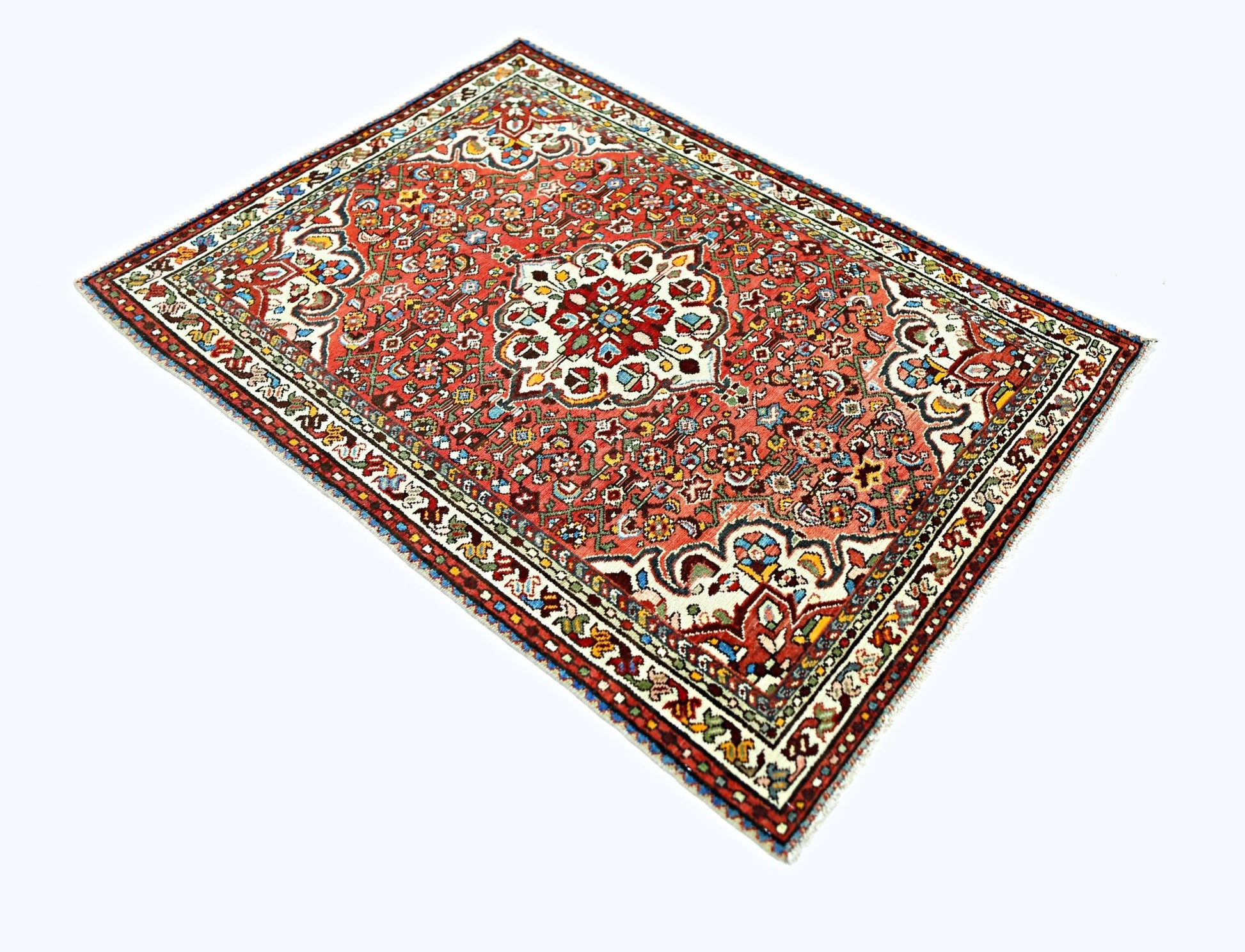 A vintage handmade Persian Sarouk rug featuring a floral medallion pattern in red and cream tones.