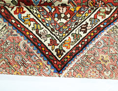 A folded vintage Persian Sarouk rug featuring intricate floral patterns in red, blue, and cream.