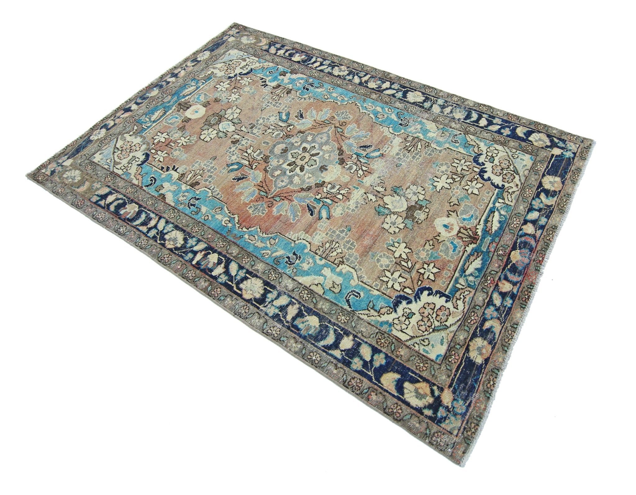 A vintage Persian Tabriz rug featuring a floral medallion pattern in blue and muted earth tones.
