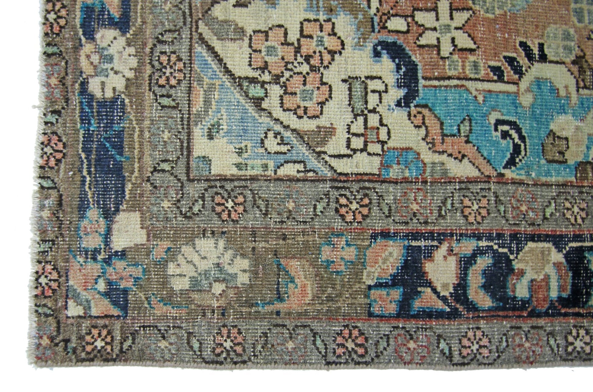 A vintage Persian Tabriz rug featuring intricate floral patterns in blue, pink, and brown tones.