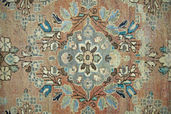 A vintage Persian Tabriz rug featuring a central floral medallion in blue and tan tones.