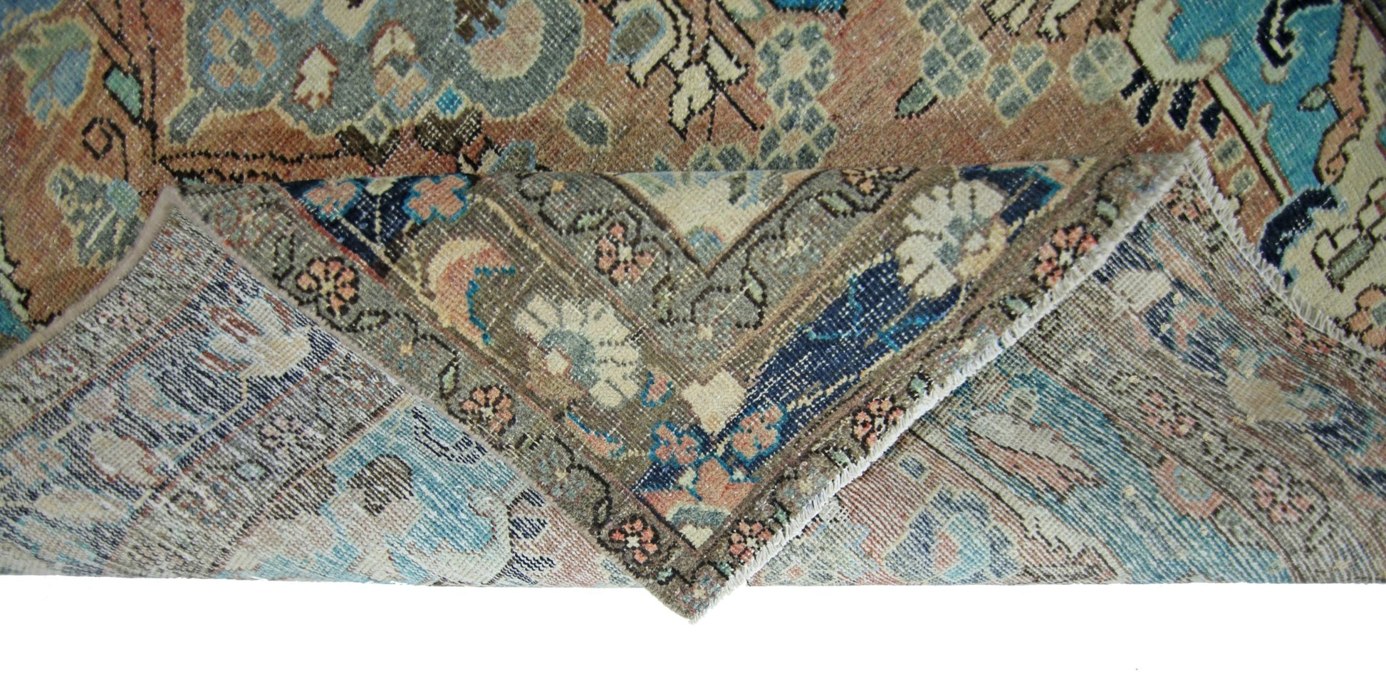 A vintage Persian Tabriz rug with a folded corner revealing its intricate floral pattern.