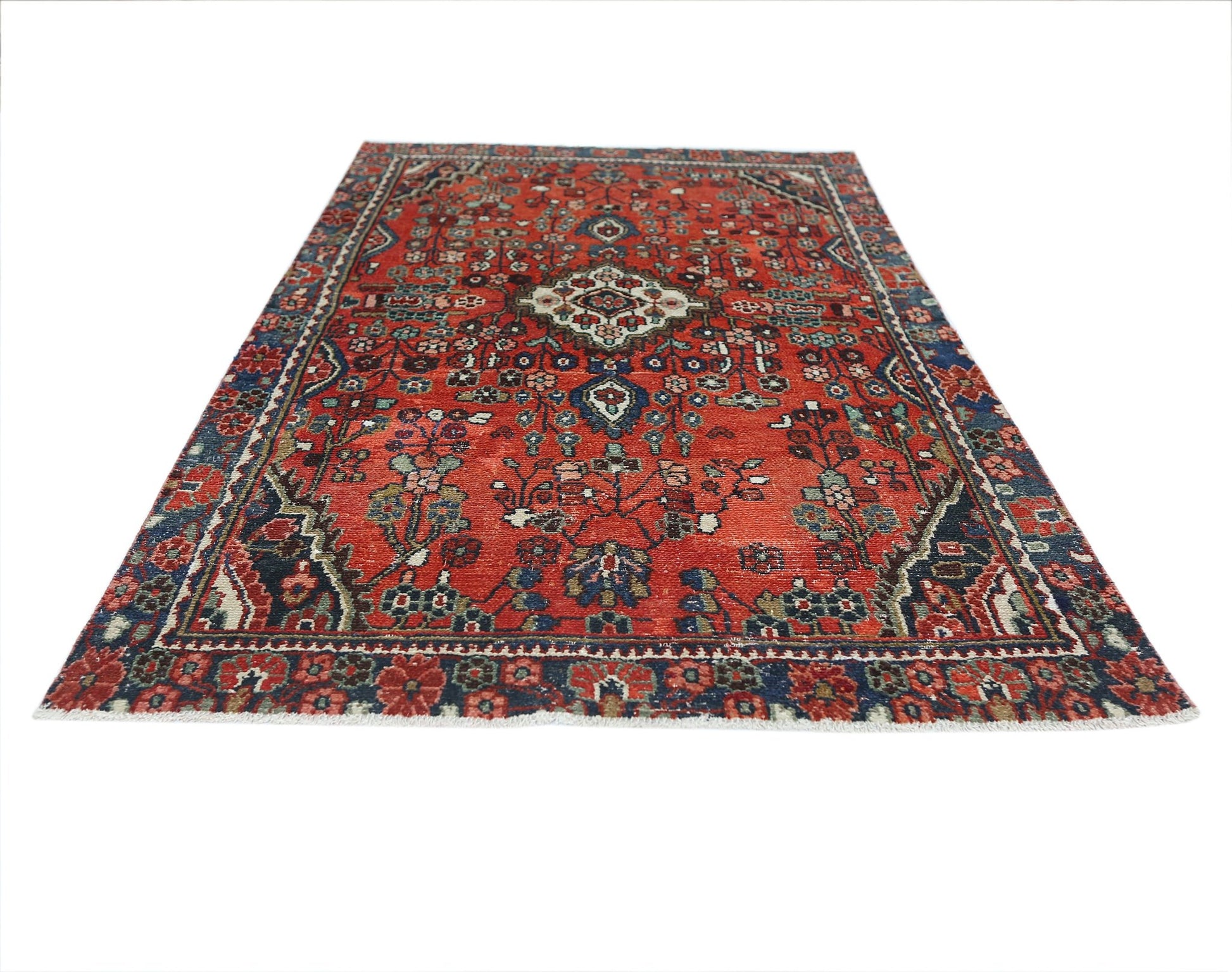 A vintage Persian Sarouk rug featuring a floral pattern in red, blue, and cream tones.
