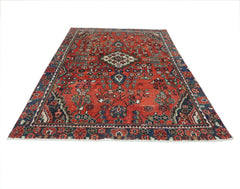 A vintage Persian Sarouk rug featuring a floral pattern in red, blue, and cream tones.