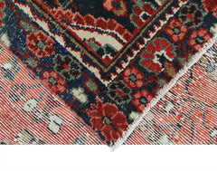A corner view of a vintage Persian Sarouk rug featuring intricate floral patterns in red and blue.