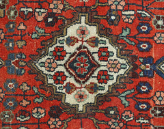 A vintage Persian Sarouk rug featuring a central floral medallion on a vibrant red background.