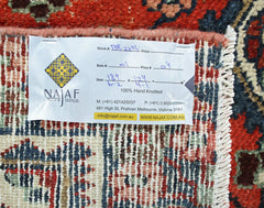 A vintage Persian Sarouk rug with a detailed floral pattern and a white product information tag.