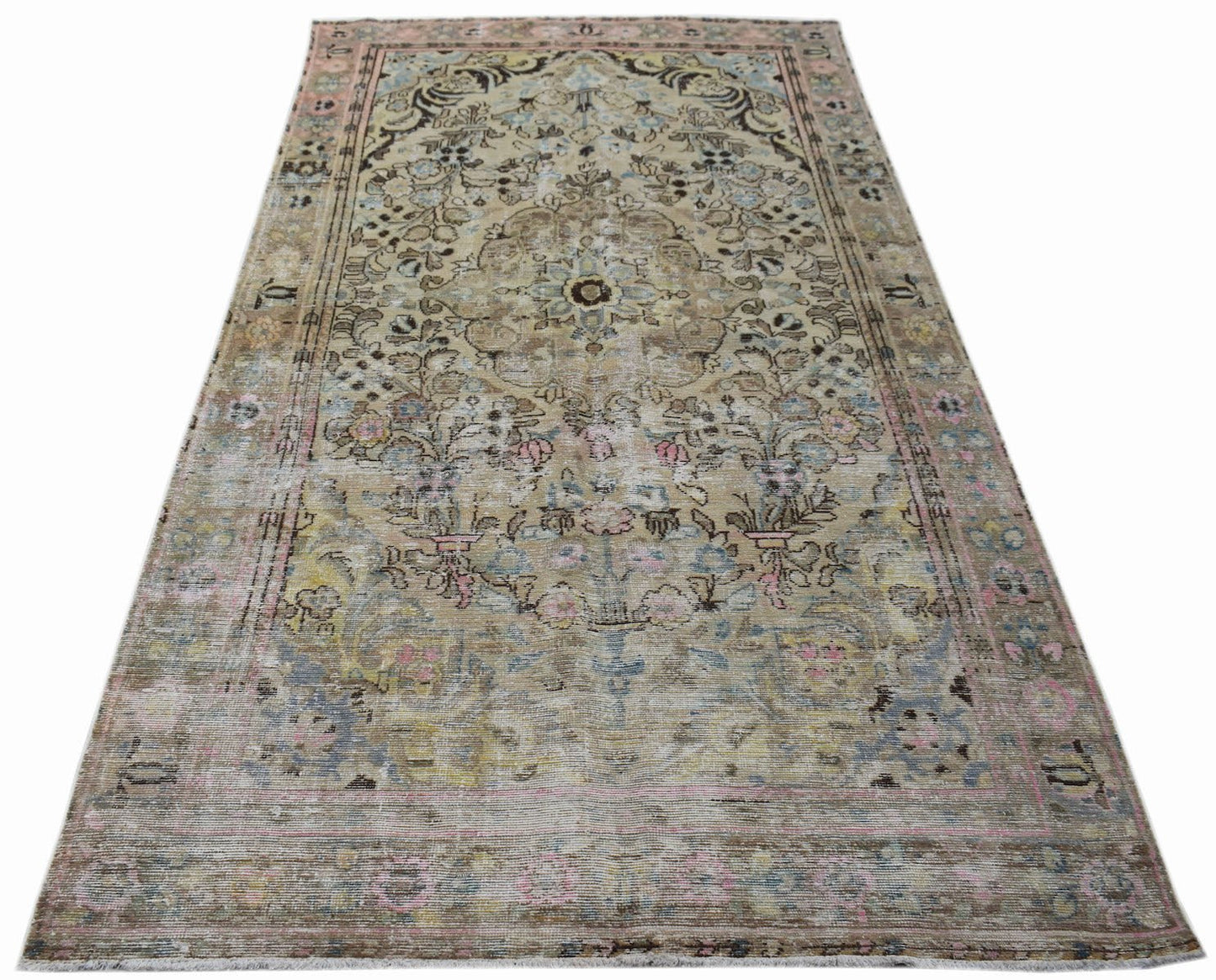 A vintage Persian Sarouk rug featuring a faded floral medallion pattern in muted earth tones.