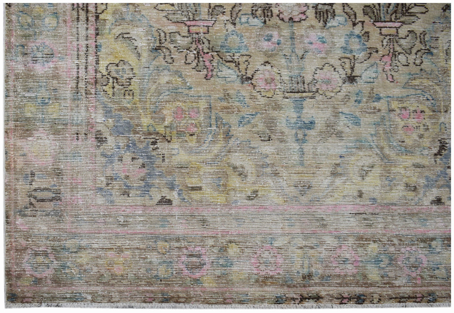 A vintage Persian Sarouk rug featuring a faded floral pattern in muted pink, blue, and yellow tones.