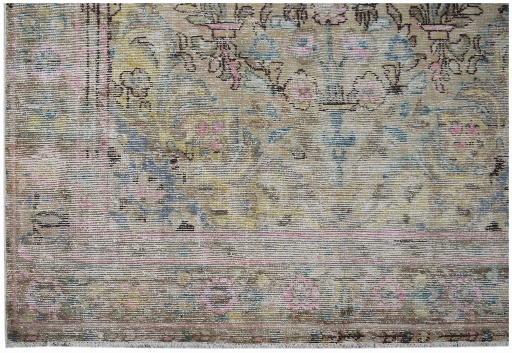 A vintage Persian Sarouk rug featuring a faded floral pattern in muted pink, blue, and yellow tones.