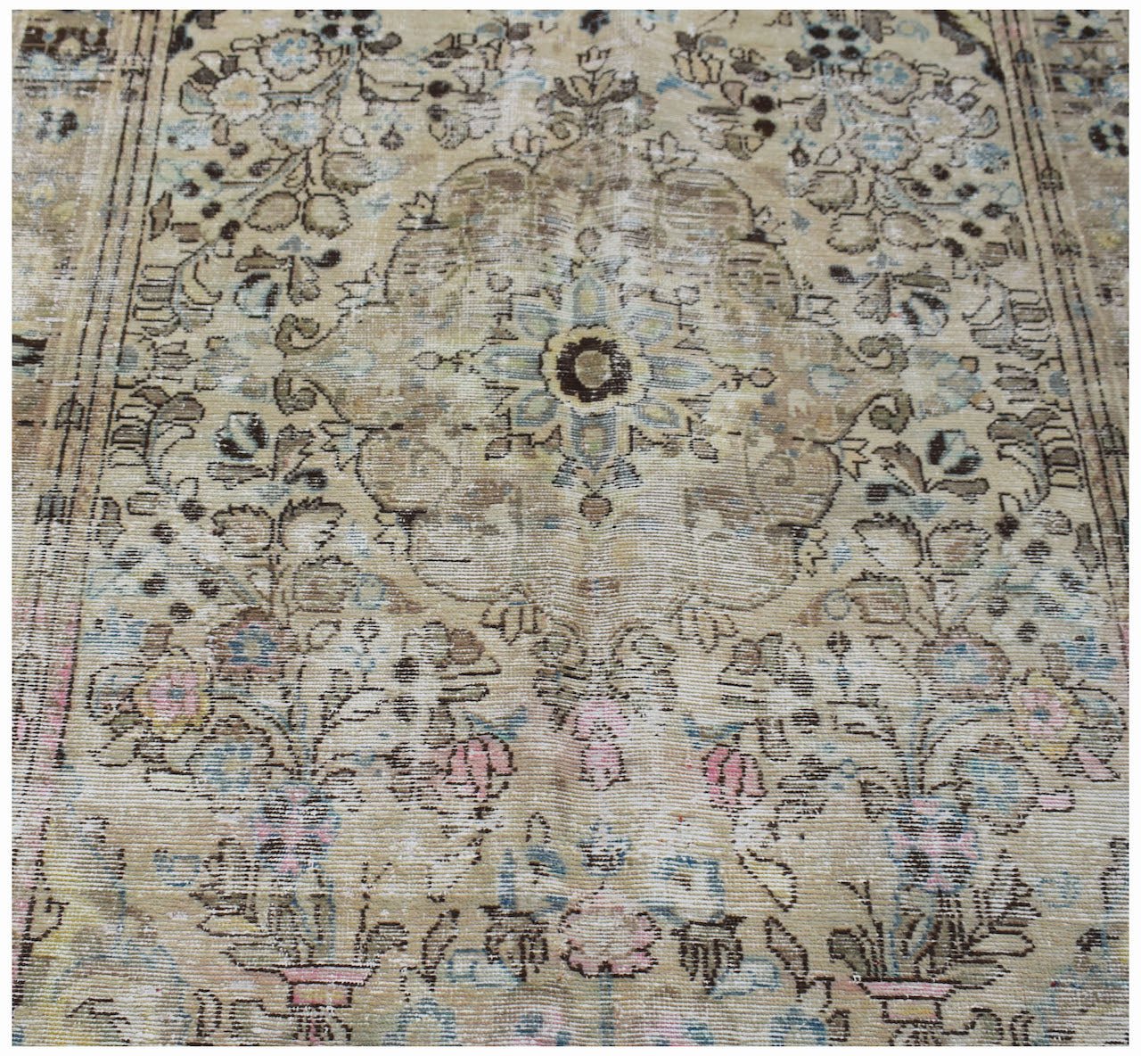 A vintage Persian Sarouk rug featuring a faded floral pattern in muted earth tones.