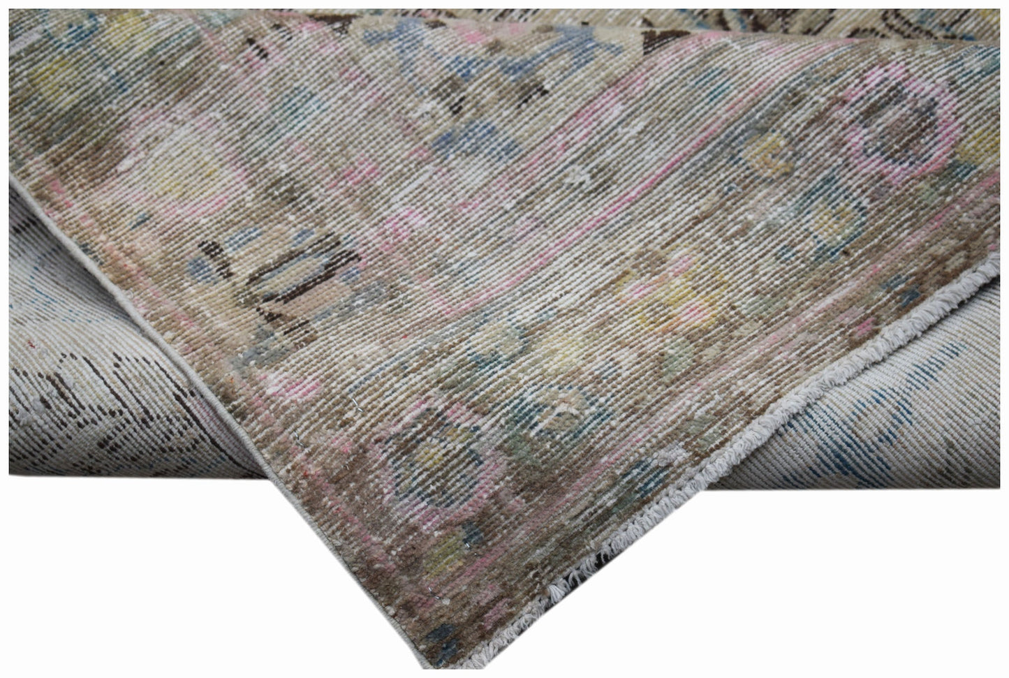 A folded vintage Persian Sarouk rug featuring a faded floral pattern in muted tones.