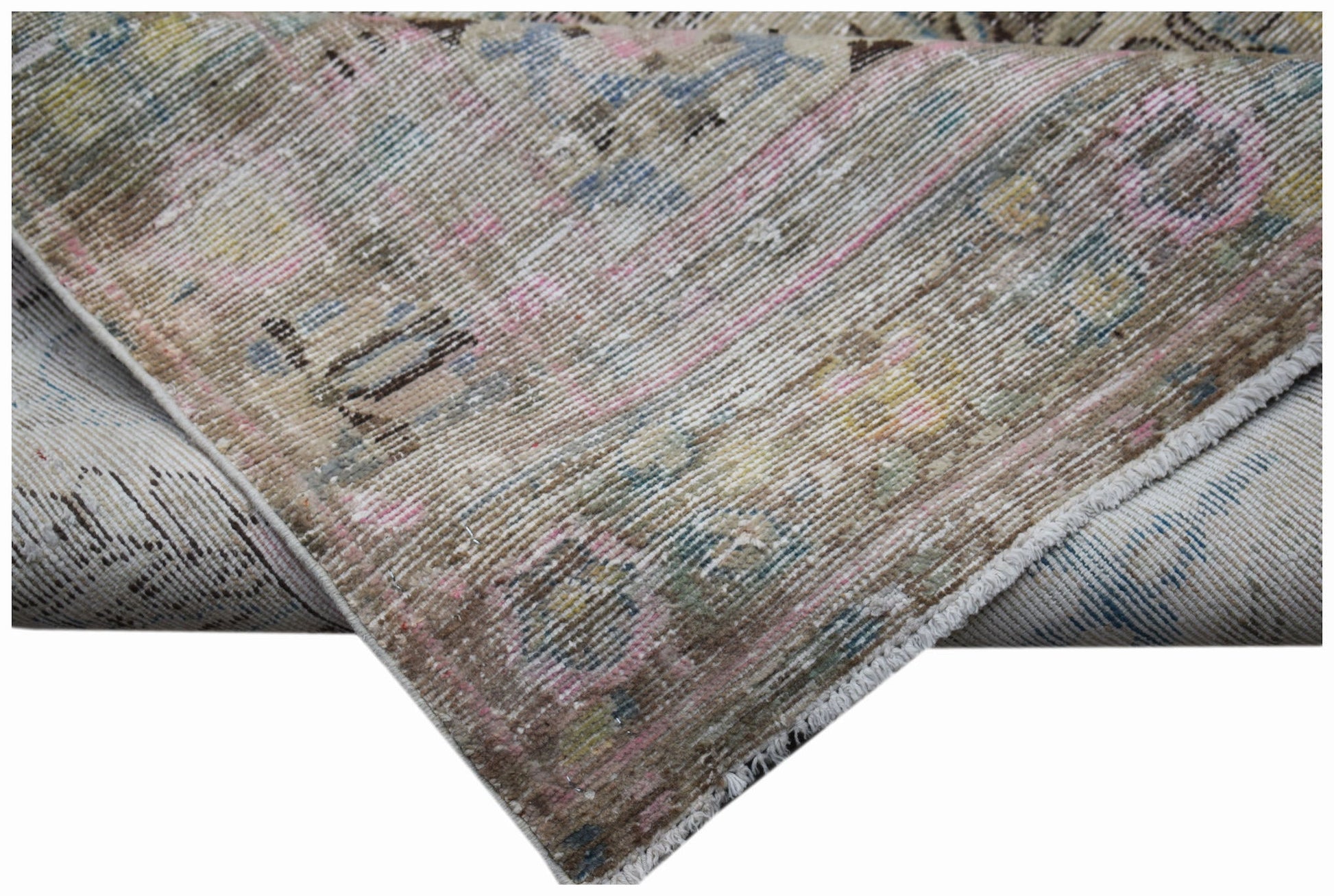 A folded vintage Persian Sarouk rug featuring a faded floral pattern in muted tones.